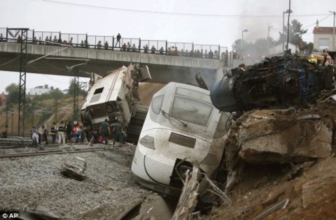 People look down from the rail bridge on the aftermath of a devastating train crash in north west Spain