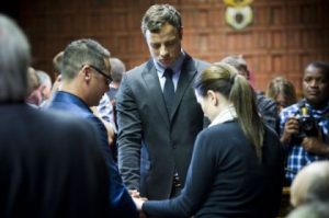 Oscar Pistorius icries as he prays with his sister Aimee and Brother Carl in the Magistrates court in Pretoria