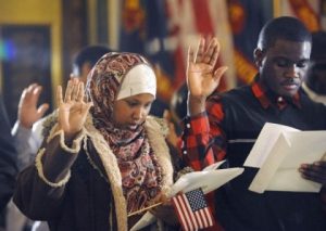 Nasra Isak, left, and Roy Maweja, right, are sworn in and naturalized as US citizens as 25 people from 18 different countries became official US citizens at the Capitol in Lansing Wednesday 12/4/2013. Isak, from East Lansing, is originally from Somalia, and Maweja, from Lansing, is originally from Congo.
