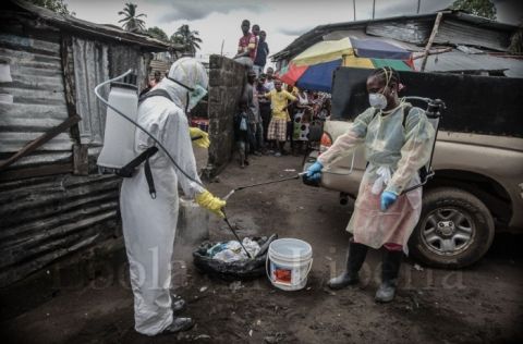 Members of the Liberian Red Cross burial team disinfect each other - Ebola crisis in Liberia