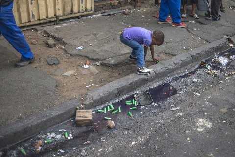 A child picks up casings from the rubber bullets fired by police in Jeppestown, Johannesburg(Mujahid Safodien:AFP)