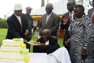 President Museveni (L) serves cake to Mzee Rubongoya in Kabarole District on Saturday. PHOTO BY Ruth Katusabe.  