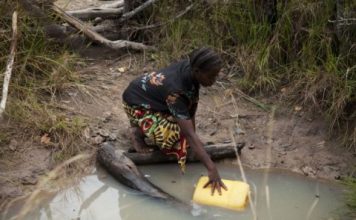 Dimitria Lubinga collecting water from an unsafe open well that is 20 minutes walk from her house, Habeenzu village, Zambia