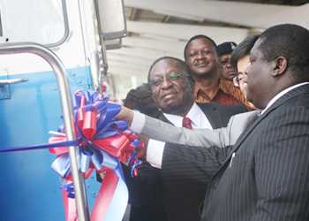 Transport minister Dr Harrison Mwakyembe (L) and Zambia's Transport, Supply and Communication minister, Yamfwa Mukanga (R) cut a ribbon at yesterday's launch in Dsm of six new SSD20 locomotives