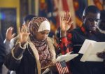 Nasra Isak, left, and Roy Maweja, right, are sworn in and naturalized as US citizens as 25 people from 18 different countries became official US citizens at the Capitol in Lansing Wednesday 12:4:2013