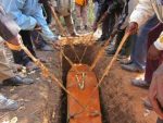 A coffin is lowered into the grave during a funeral in a Zambian village. At the end of the ceremony, the family members shovel soil back on top