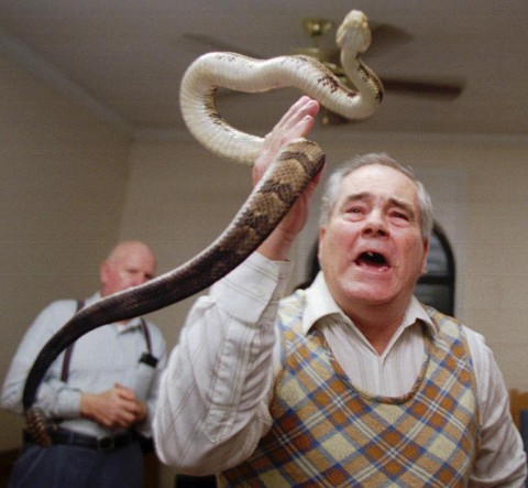 In this Feb. 25, 1995 file photo, Junior McCormick tests his faith by handling a rattlesnake as Homer Browing looks on during services at the Church of the Lord Jesus in Kingston, Ga. Church members believe that if they have faith in God, they will be protected from harm as they handle the serpents. (AP Photo/John Bazemore)