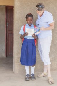 Project Luangwa charity manager Karen Beattie helps a local student with her schoolwork. (Photograph by Marcus and Kate Westberg)