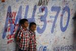 Two Malaysian children stand in front of messages board and well wishes to people involved with the missing Malaysia Airlines jetliner MH370, Sunday, March 16, 2014