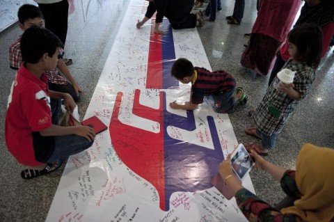 Visitors write on a banner carrying messages for the passengers of missing Malaysia Airlines flight MH370 at Kuala Lumpur International Airport (KLIA) in Sepang, outside Kuala Lumpur