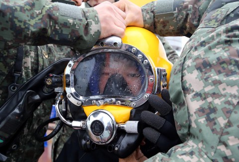 A diver wears a helmet to look for people still missing from the sunken ferry Sewol, in the water off the southern coast near Jindo, South Korea, Saturday, April 26, 2014