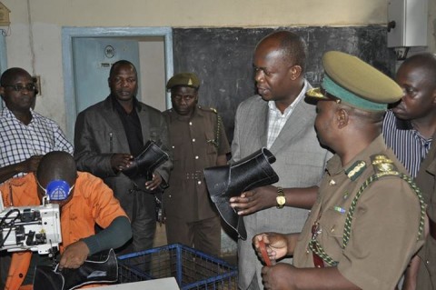 ZAMBIA PRISONS SERVICE COMMISSIONER PERCY CHATO ADMIRING PART OF A BOOT MADE BY INMATES AT TANZANIA PRISONS SHOE MAKING WORKSHOP.