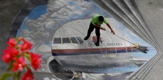 A school utility worker mops a mural depicting the missing Malaysia Airlines Flight 370 Tuesday,