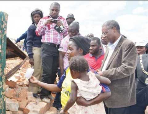 LOCAL Government and Housing Minister Emmanuel Chenda listens to Elizabeth Bwalya explaining the extent of damage to her house in Mindolo North in Kitwe yesterday. Picture By MOFFAT CHAZINGWA