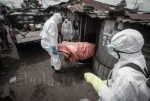 Dressed in protective clothing, Garmai Sumo and his colleagues carry the body of 40-year-old Mary Nyanforh from her house – Ebola crisis in Liberia