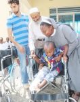 Italian Hospital Acting Administrator Sr. Ireen Kunda  placing   Philip Kusa, 4 years old and Chipata resident,  in his newly donate wheel chair