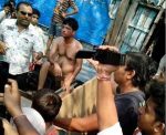 Kumar, middle, is stripped naked and awaits his fate, as locals record the punishment he is about to face