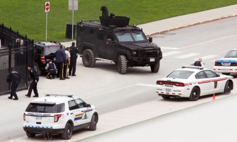 Police take cover near Parliament Hill after the shootings. Photograph- Chris Wattie:Reuters