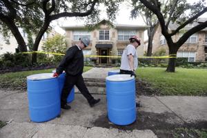 Protect Environmental workers move disposal barrels to a staging area outside the apartment of a hea …