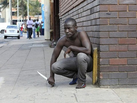 A city in lockdown ... a foreign national holds a knife following clashes between a group