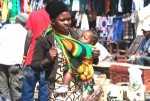 A mother carrying a baby in front using a chitenje cloth in Lusaka. It is easier to breast feed the baby if needed.