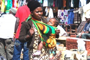 A mother carrying a baby in front using a chitenje cloth in Lusaka. It is easier to breast feed the baby if needed.