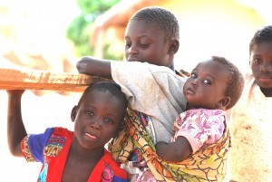Girl carrying her baby sister on the her back. Her back is small enough for the baby to feel comfortable. This was in a village in Zambia.