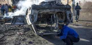 People look at a burnt-out car after foreign nationals reportedly torched it in the early hours outside a hostel in the Jeppestown area, east of Johannesburg(Mujahid Safodien:AFP)