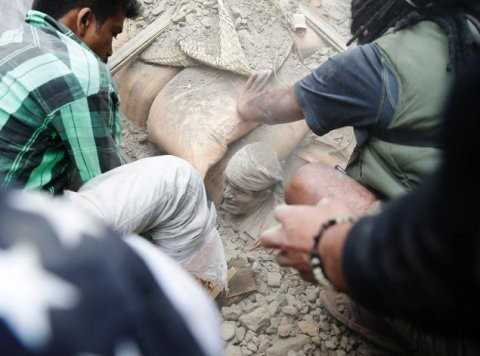 People try to free a man from the rubble of a destroyed building after an earthquake hit Nepal, in Kathmandu, Nepal, April 25, 2015.