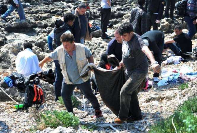 Men carry a body inside a blanket on the Rhodes seashore. Photograph- Nikolas Nanev:AP