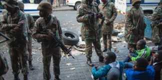 South African police and soldiers guard migrants after raiding buildings in Johannesburg's central business district on May 8, 2015 in an operation where over 300 illegal immigrants and foreign nationals were arrested (AFP Photo/Mujahid Safodien)